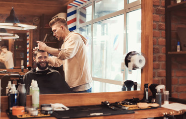 Professional barber working with client in hairdressing salon