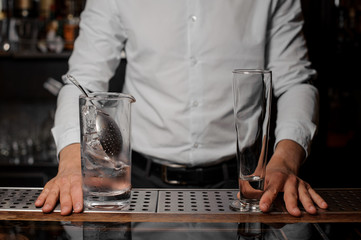 Bartender standing behind the bar counter with glasses on it