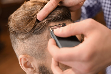 Professional barber working with client in hairdressing salon