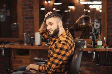 Handsome man with trendy hairstyle in barbershop
