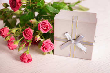 Gift box and beautiful flowers on light background