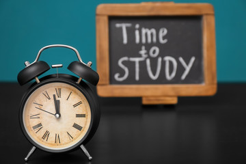 Alarm clock and chalkboard with phrase "Time to study" on table. Management concept