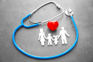 Family figure, red heart and stethoscope on grey background. Health care concept