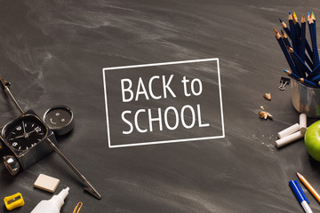 school supplies, alarm, pencils, apple on black chalkboard top view, copy space. concept: back to school background,