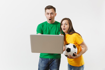 Shocked couple woman man, football fans in yellow green t-shirt cheer up support team with soccer ball, watching game on pc laptop isolated on white background. Sport family leisure lifestyle concept.