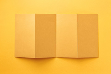 Mockup of opened four fold golden foil brochure isolated at paper background.