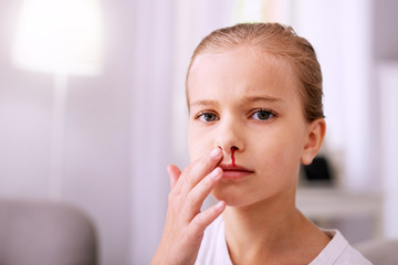 Sad mood. Portrait of a sad cheerless girl while having blood from her nose