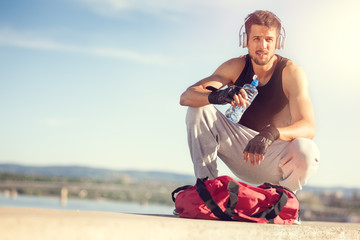 Young man resting next river after workout