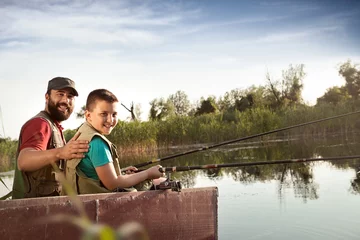 Fotobehang Vader en zoon vissen vanaf boot op rivier © Cherries