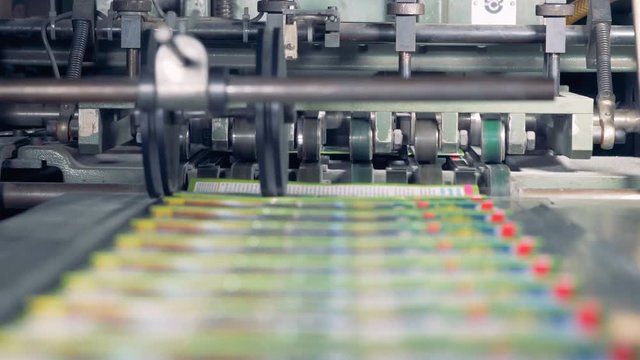 Factory equipment pushes colorful books on a conveyor, close up.