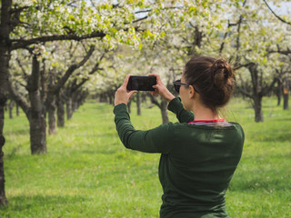 Young woman taking a picture of the view while hiking in a national park with a smart phone