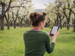 Rear view of a young woman outdoors reading on her ebook