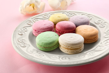 Plate with tasty macarons on color background