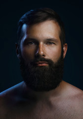 Close-up portrait of a brutal bearded man. Low key dark blue light