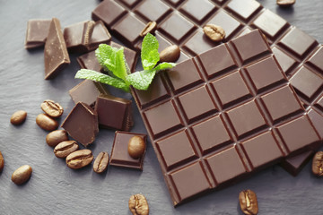 Tasty dark chocolate and coffee beans on table