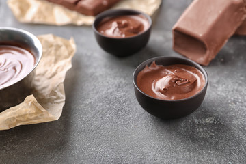 Bowls with tasty melted chocolate on grey table