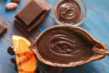 Tasty melted chocolate in cocoa pod on wooden table