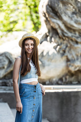 portrait of beautiful smiling woman with long hair in straw hat on street