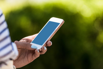 partial view of woman with smartphone in hand on street