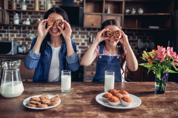 daughter and mother covering eyes with cookies