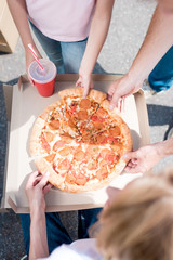 cropped shot of family with daughter taking slices of pizza
