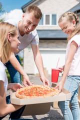 happy family with daughter preparing to eat pizza