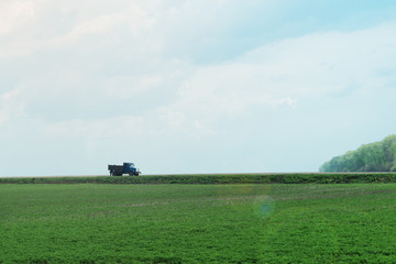 Green field with lonely truck on road