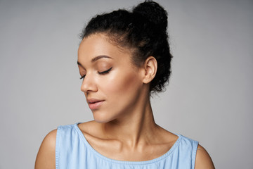 Closeup portrait of beautiful tender mixed race caucasian - african american woman with closed eyes, isolated on gray background