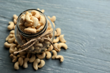 Glass jar with tasty cashew nuts on wooden background