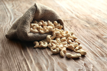 Sack with tasty cashew nuts on wooden table