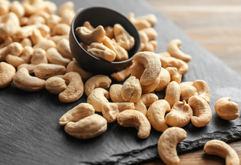 Small bowl and tasty cashew nuts on slate plate