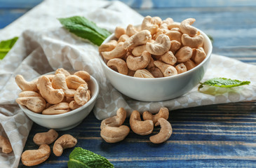 Bowls with tasty cashew nuts on  wooden background