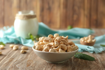 Plate with tasty cashew nuts on wooden table