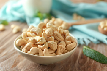 Plate with tasty cashew nuts on wooden table