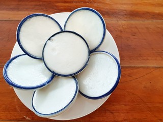 Thai dessert style, Top view coconut Milk Custard on white dish , Khnom Tuay on wooden background.