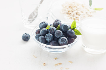 Bluberries in glass with oat flakes and milk for healthy breakfast