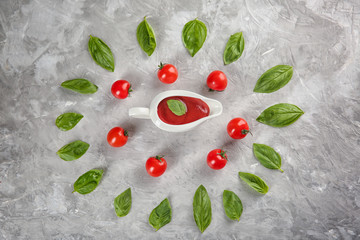 Flat lay composition with red sauce, cherry tomatoes and basil on grey background