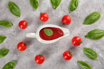 Flat lay composition with red sauce, cherry tomatoes and basil on grey background