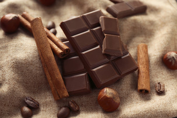 Tasty chocolate, cinnamon sticks and coffee beans on cloth