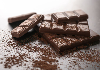 Tasty milk chocolate and cocoa powder on table