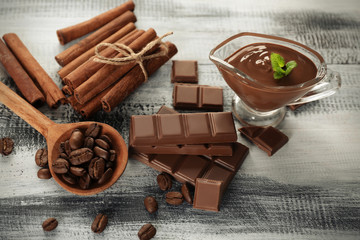 Composition with tasty chocolate, cinnamon sticks and coffee beans on wooden background