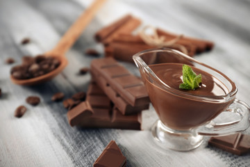 Gravy boat with tasty molten chocolate on wooden table
