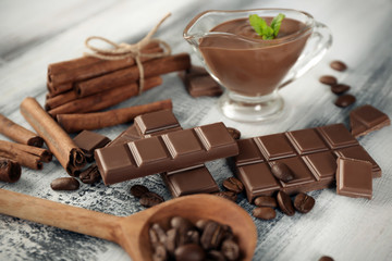 Composition with tasty chocolate, cinnamon sticks and coffee beans on wooden background