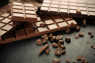 Tasty chocolate and coffee beans on table