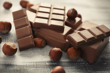 Tasty chocolate and hazelnuts on wooden background