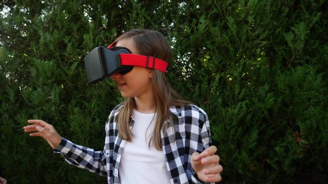 Young girl watch virtual reality in VR glasses teenager twins sisters funny hang out on backyard