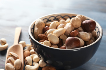 Bowl with different nuts on wooden table, closeup