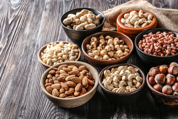 Bowls with different nuts on wooden table