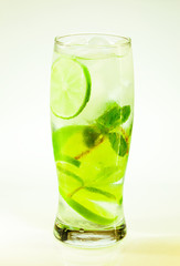 summer cold drink mojito lime and mint with ice and soda with drops on a glass on a white background