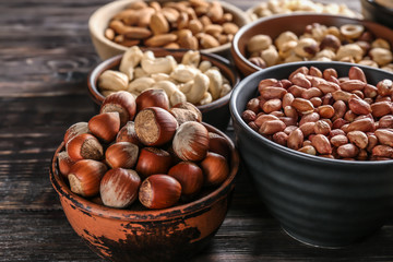 Bowls with different nuts on wooden table